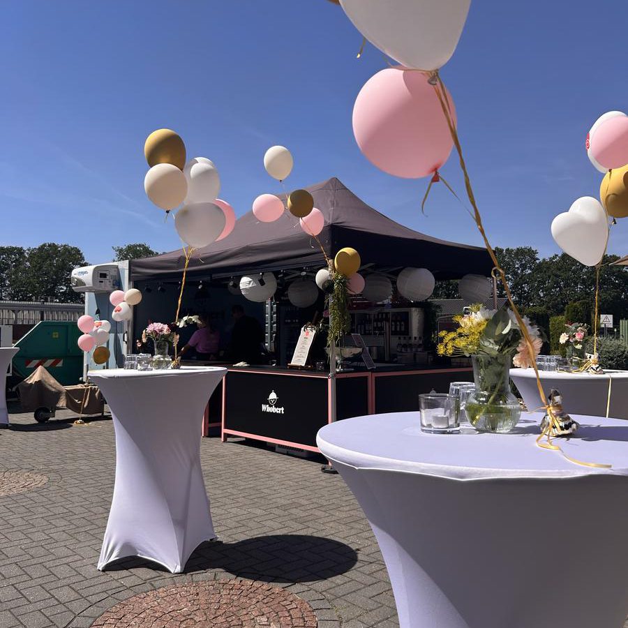 Whobert Cateringstand mit Ballondekoration bei einem Kundenevent im Freien, Stehtische mit Blumen im Vordergrund