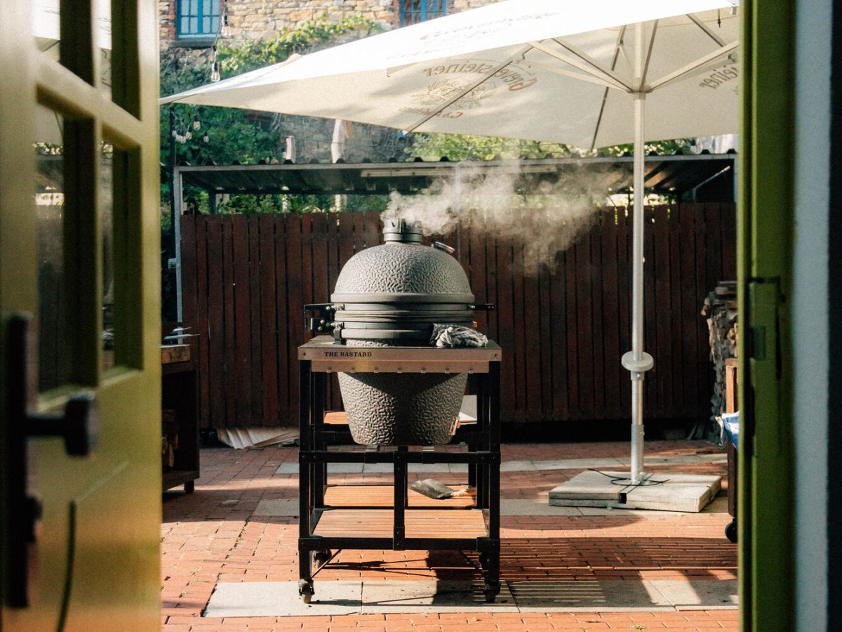 Blick durch die offene Tür in den Whobert Backyard mit Grill und Sonnenschirm