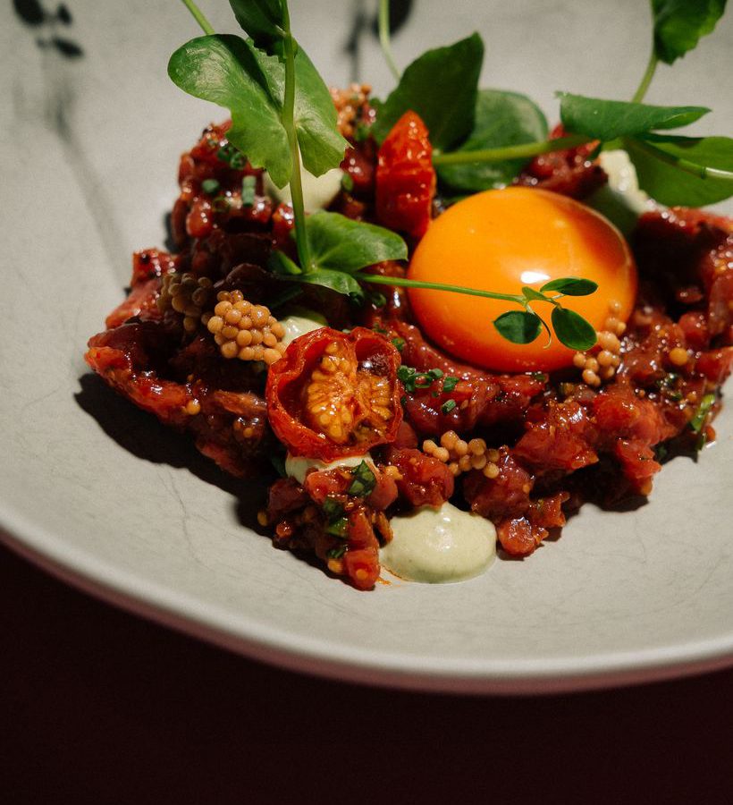 Beef Tatar mit Eigelb, angerichtet auf hellem Teller