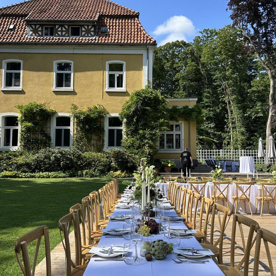 Lange eingedeckte Tafel im Garten des Landsitz Diek vor der gelben Gutsvilla