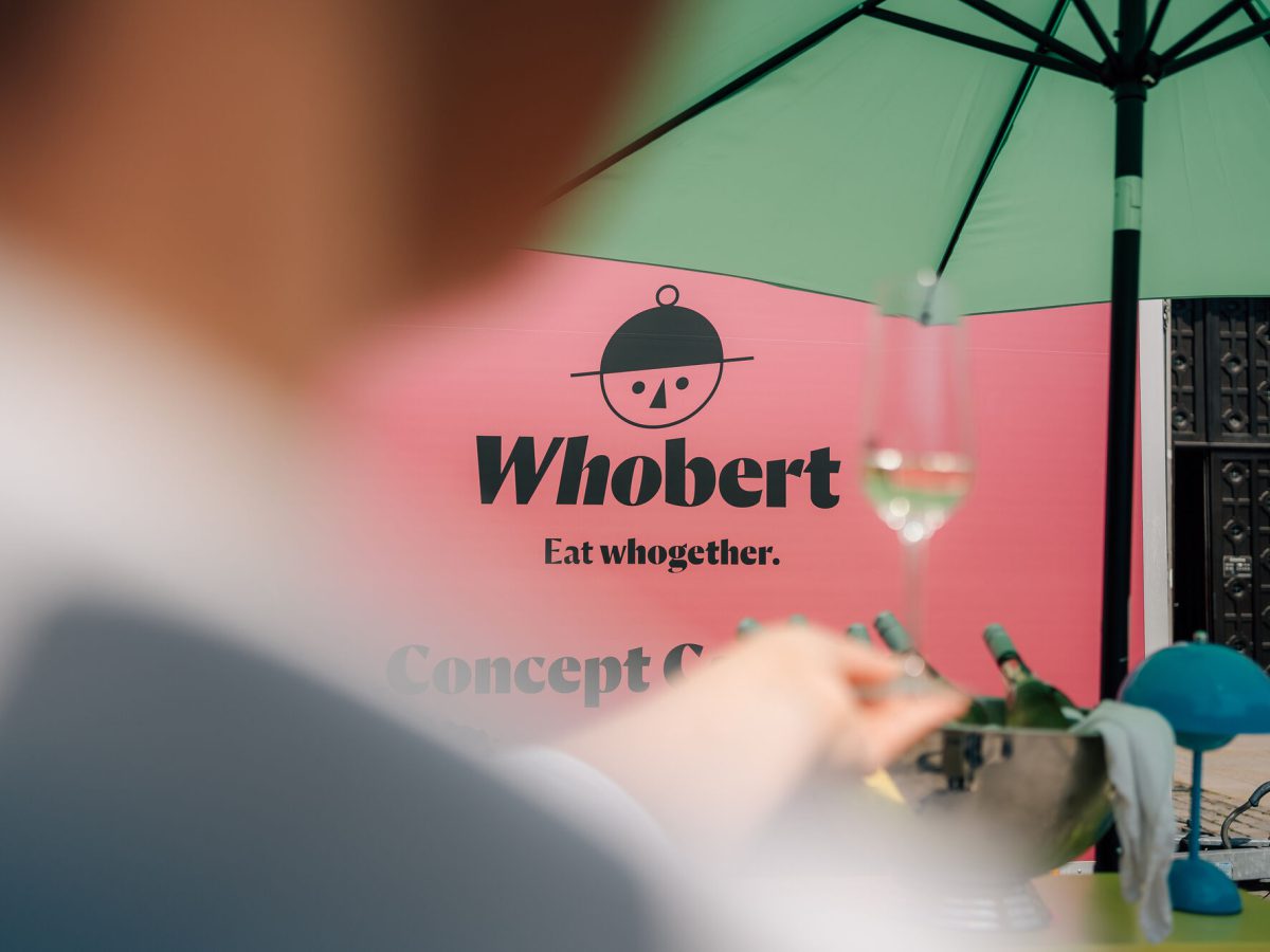 Schriftzug Whobert Concept Catering auf der pinken Wand des Cateringstands