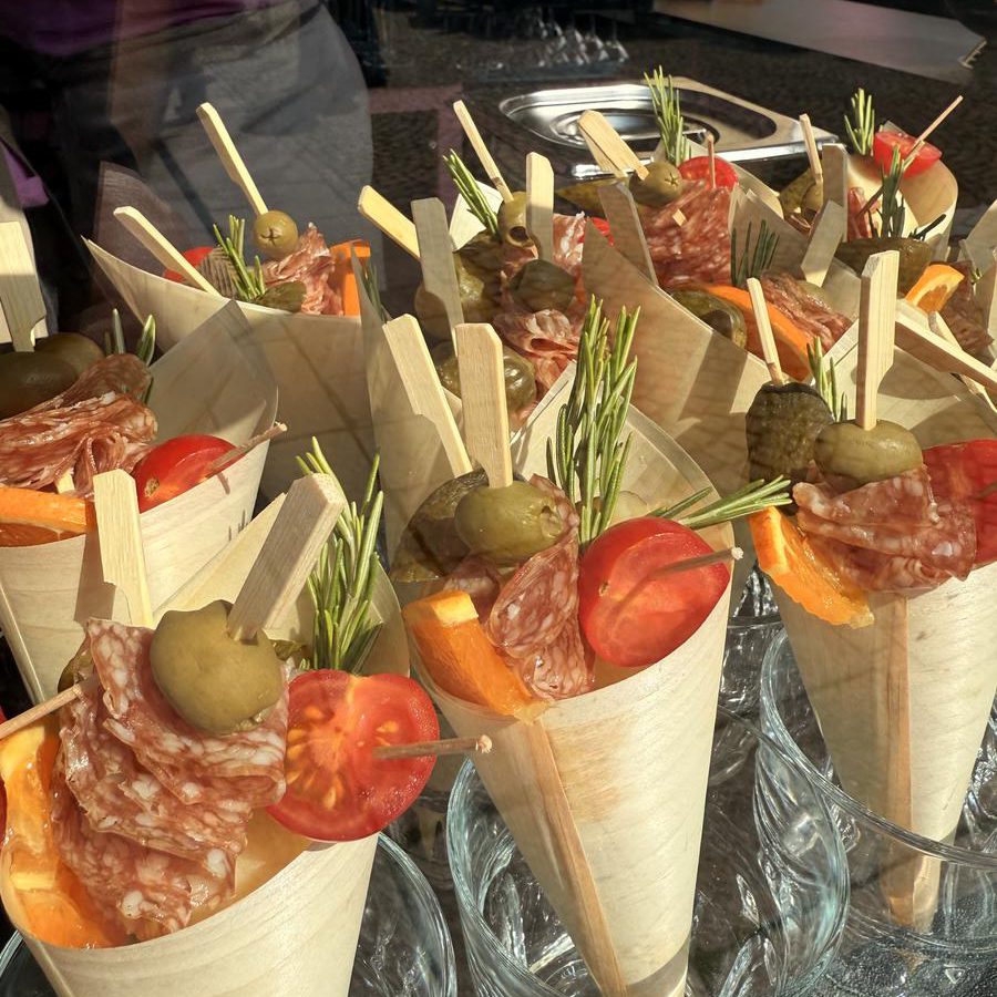 Papierspitztüten mit Salami, Oliven, Tomate und Orange als Fingerfood beim Catering angerichtet