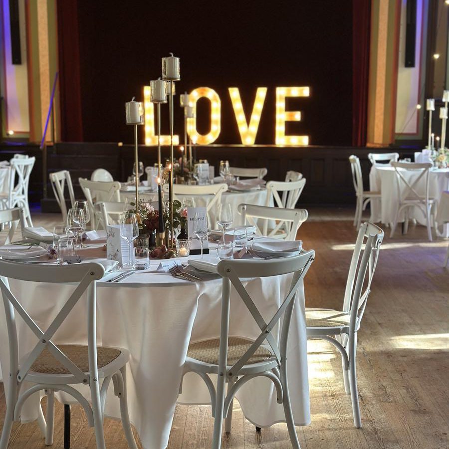 Eingedeckte Hochzeitstafel mit Kerzenleuchtern vor leuchtender LOVE-Buchstabendeko im Studio Who