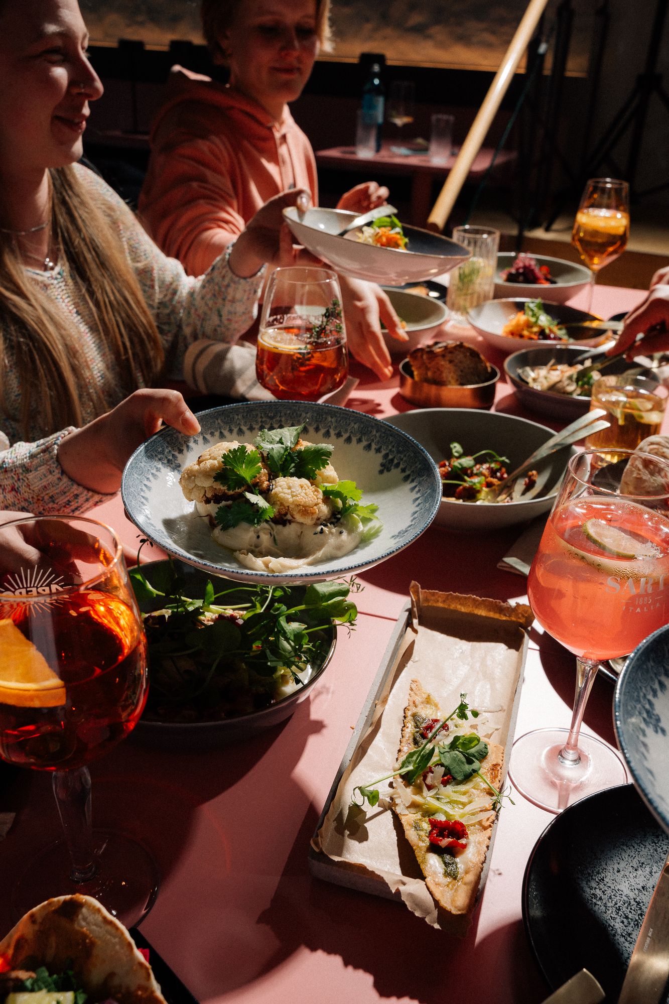 Gäste reichen sich Schalen über die rosa Tafel im Whobert Restaurant