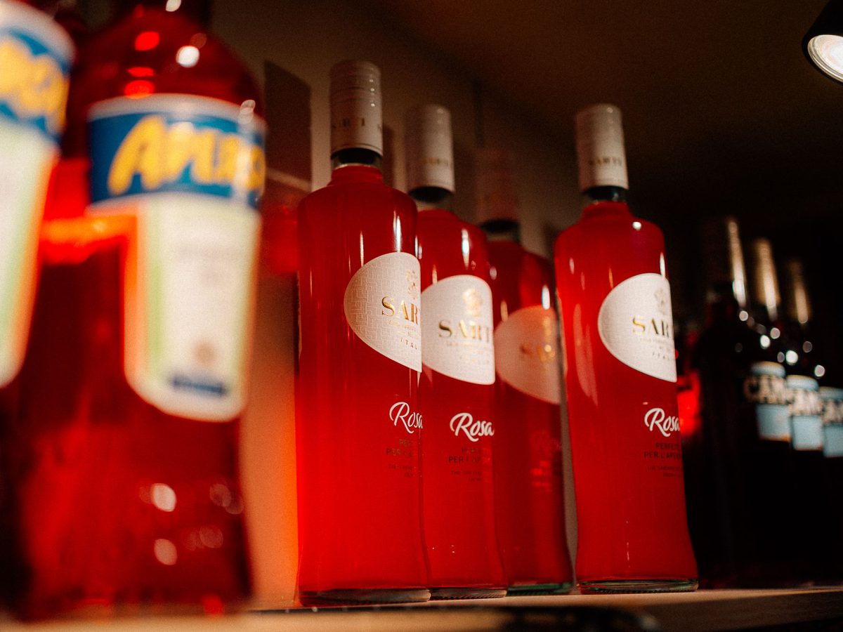 Aperitif-Flaschen im rot beleuchteten Regal der Spritzeria