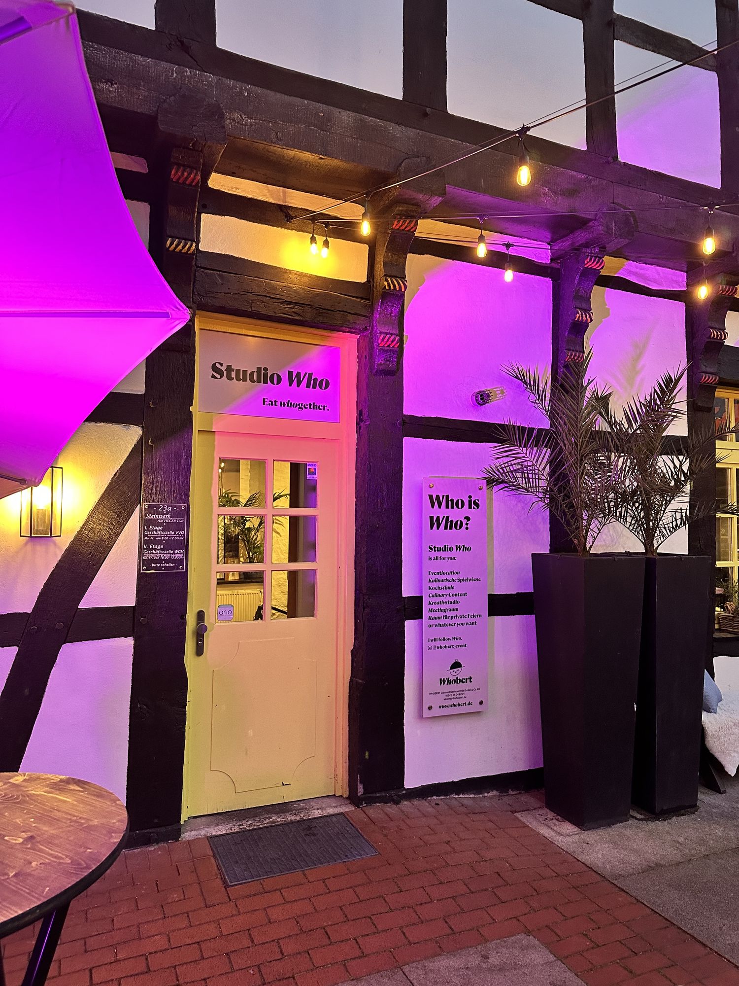 Eingang zum Studio Who: gelbe Tür im Fachwerk, abends pink beleuchtet