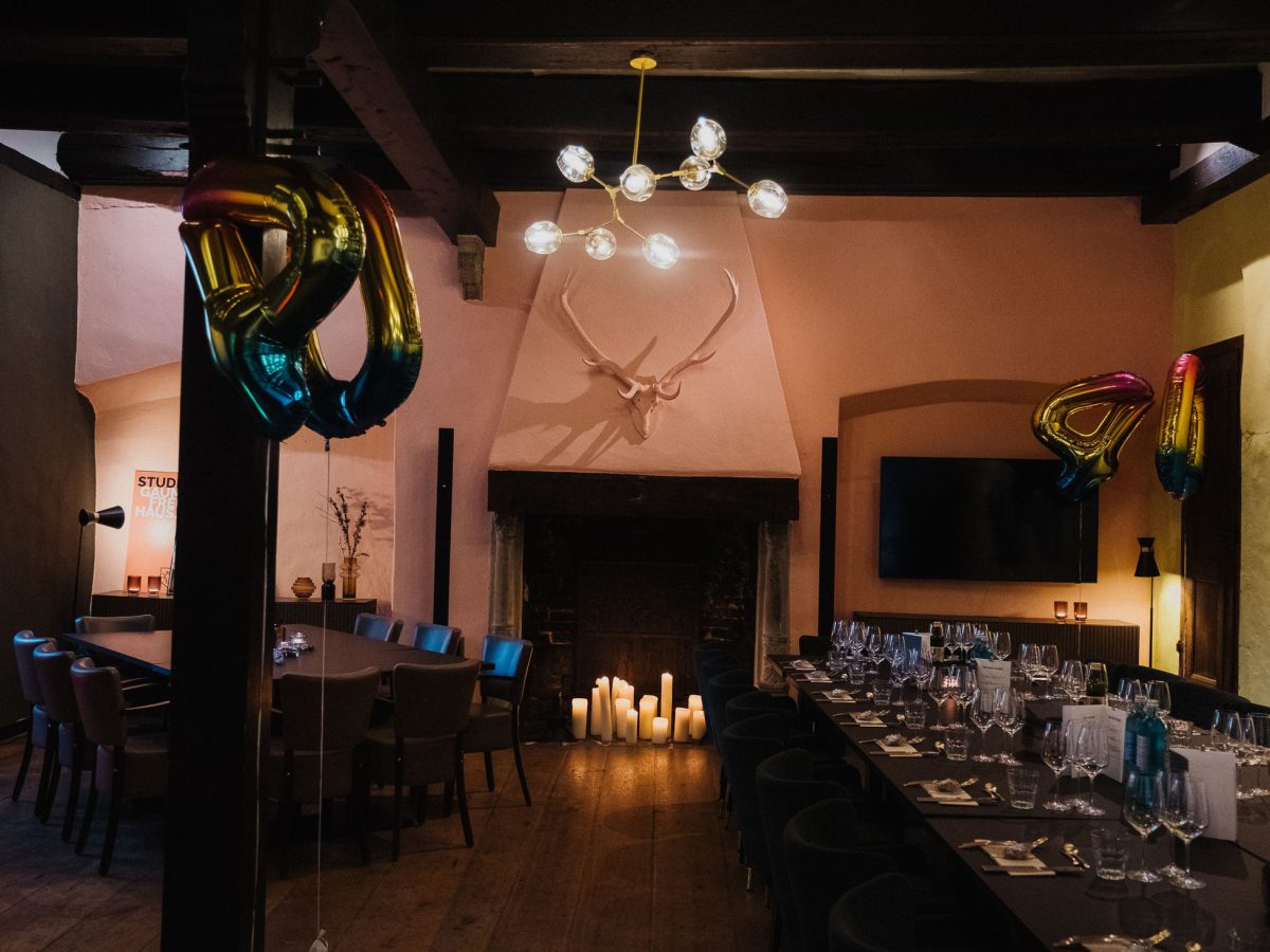Eventsaal im Studio Who mit langer eingedeckter Tafel, Kamin und alten Balken