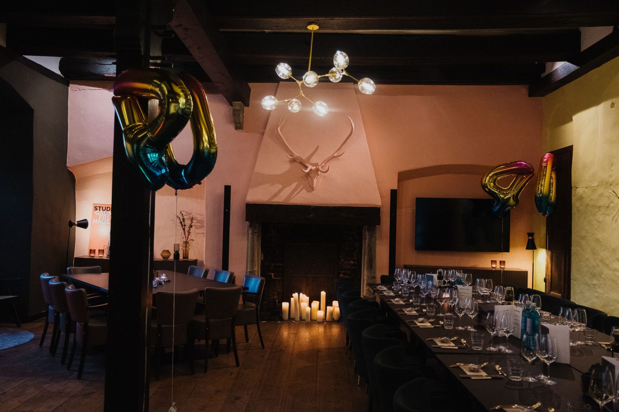 Eventsaal im Studio Who mit langer eingedeckter Tafel, Kamin und alten Balken