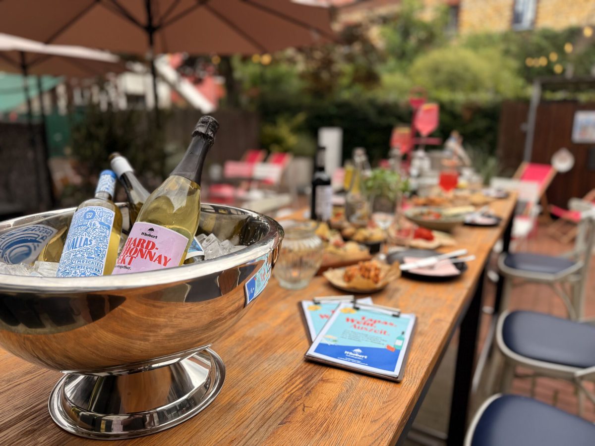 Eingedeckte Holztafel mit Sektkübel unter dem Sonnenschirm